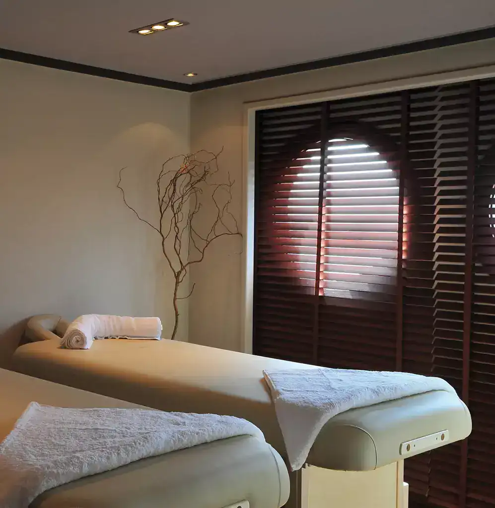 Spa treatment room aboard the M/S City & Sea Adonis with massage beds and dark wooden shutters.