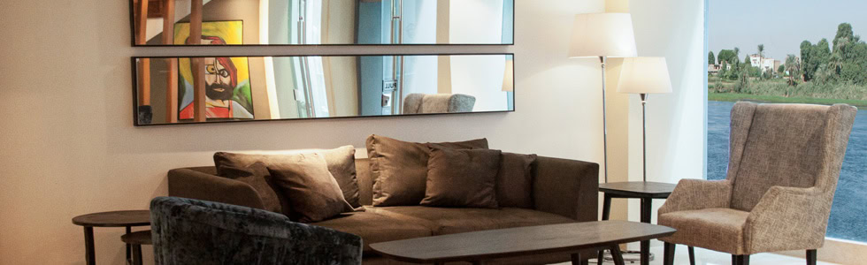 Elegant lounge aboard the M/S City & Sea Adonis with brown sofa and Nile River view.