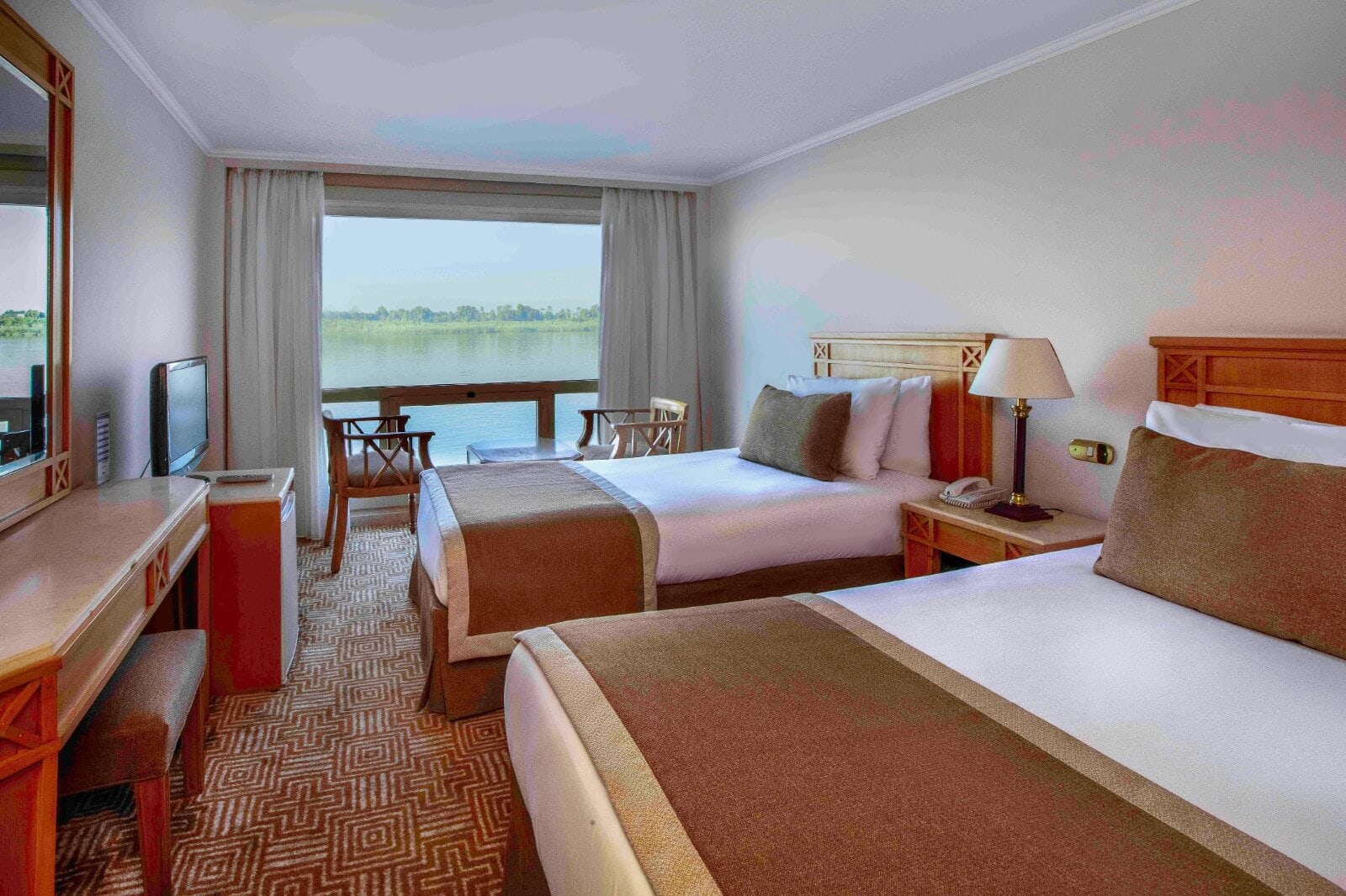 Spacious cabin aboard M/S City & Sea Adonis with twin beds and Nile River view from balcony.