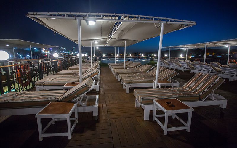 Sun deck aboard the M/S City & Sea Adonis at night with loungers and shaded seating areas.