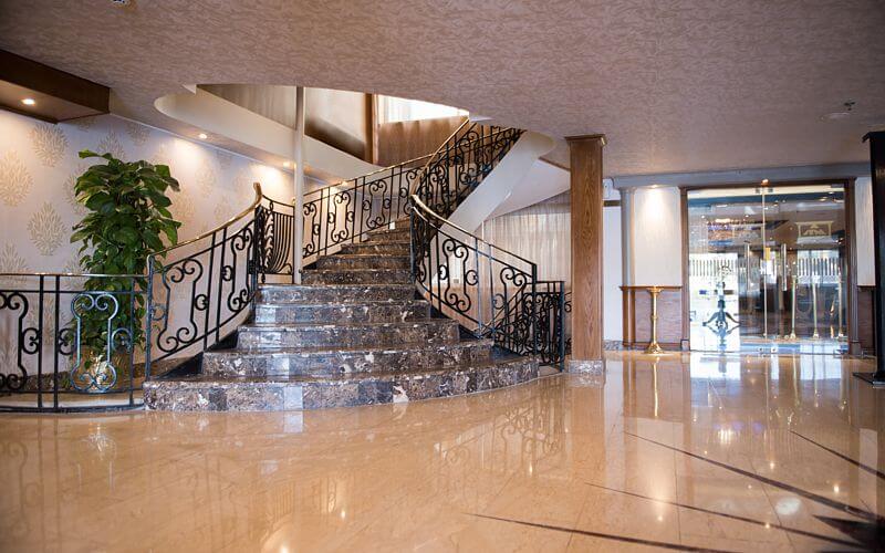 Elegant lobby with marble staircase and ornate iron railings aboard M/S City & Sea Adonis.