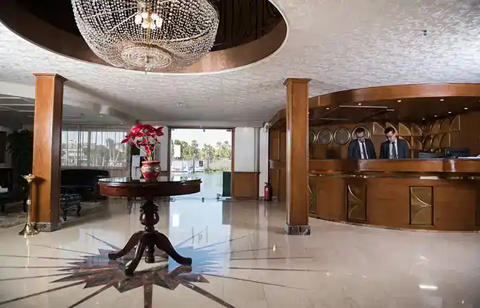 Fairmont Nile City Cairo lobby with marble floors, wooden reception desk and elegant chandelier.
