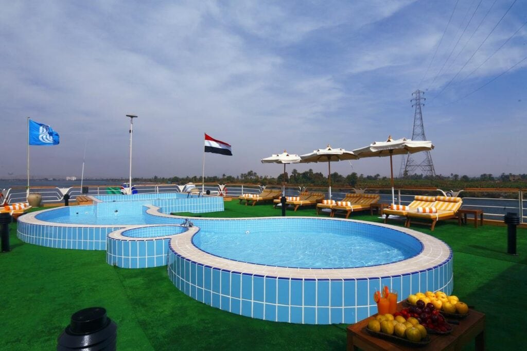 Sun deck aboard the M/S City & Sea Adonis with pools, loungers and Egyptian flag.