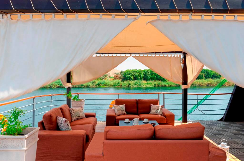 Shaded lounge area aboard the M/S City & Sea Adonis with terracotta seating overlooking the Nile River.